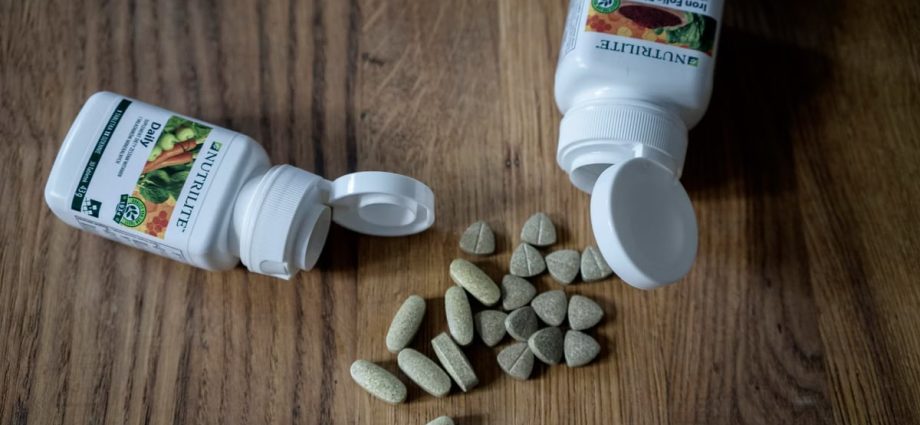 Top view of set of various medical pills arranged near plastic containers on wooden table